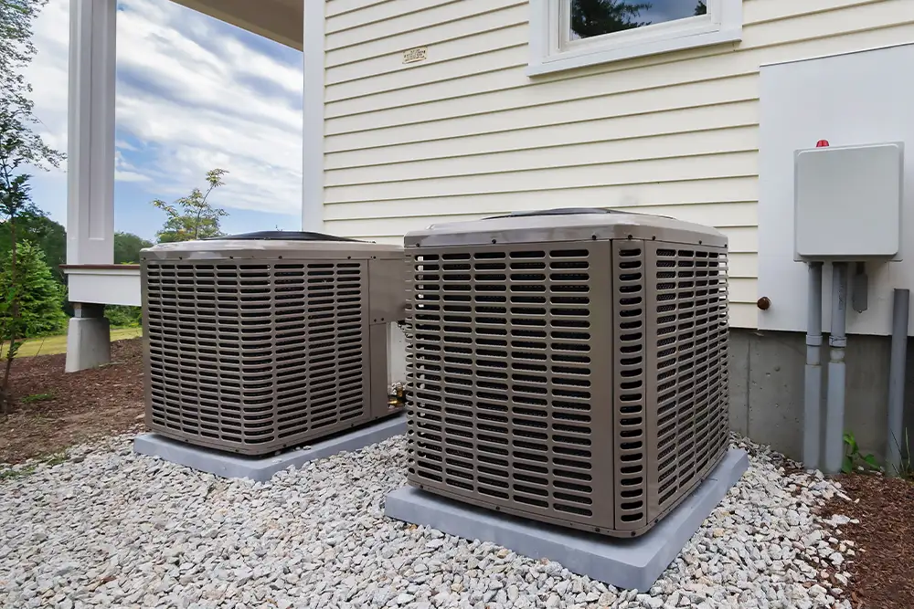 Outdoor condenser units on gravel beside a house